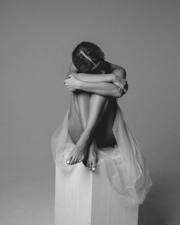 Woman in a flowing, gentle movement pose in a studio with mint light.